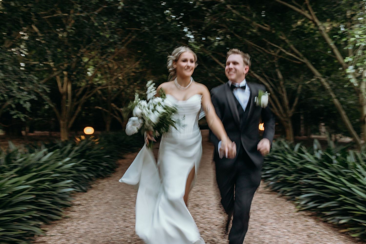 Couple walking along garden path during wedding photoshoot.