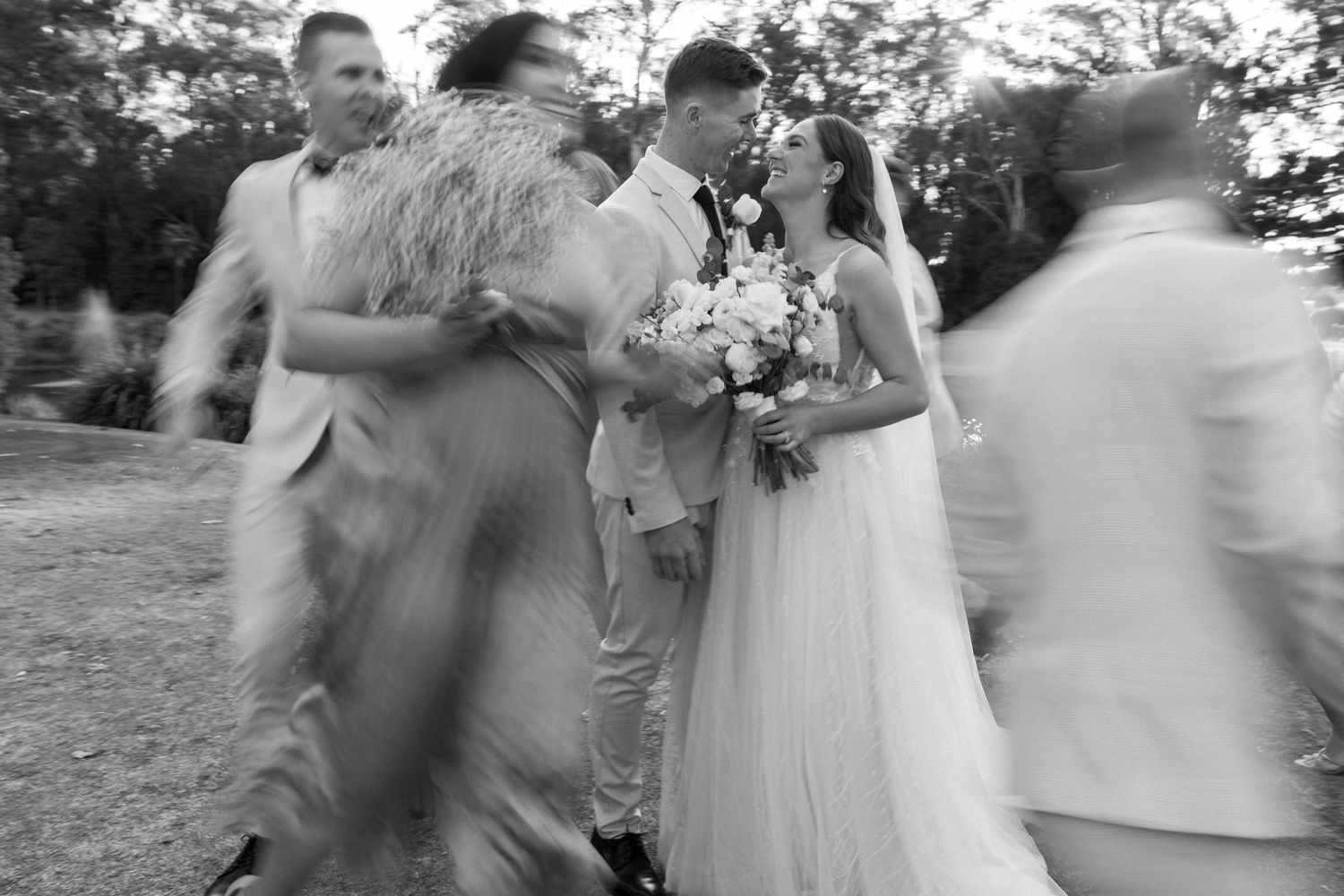 Wedding party celebrates with joyful movement and dancing outdoors.