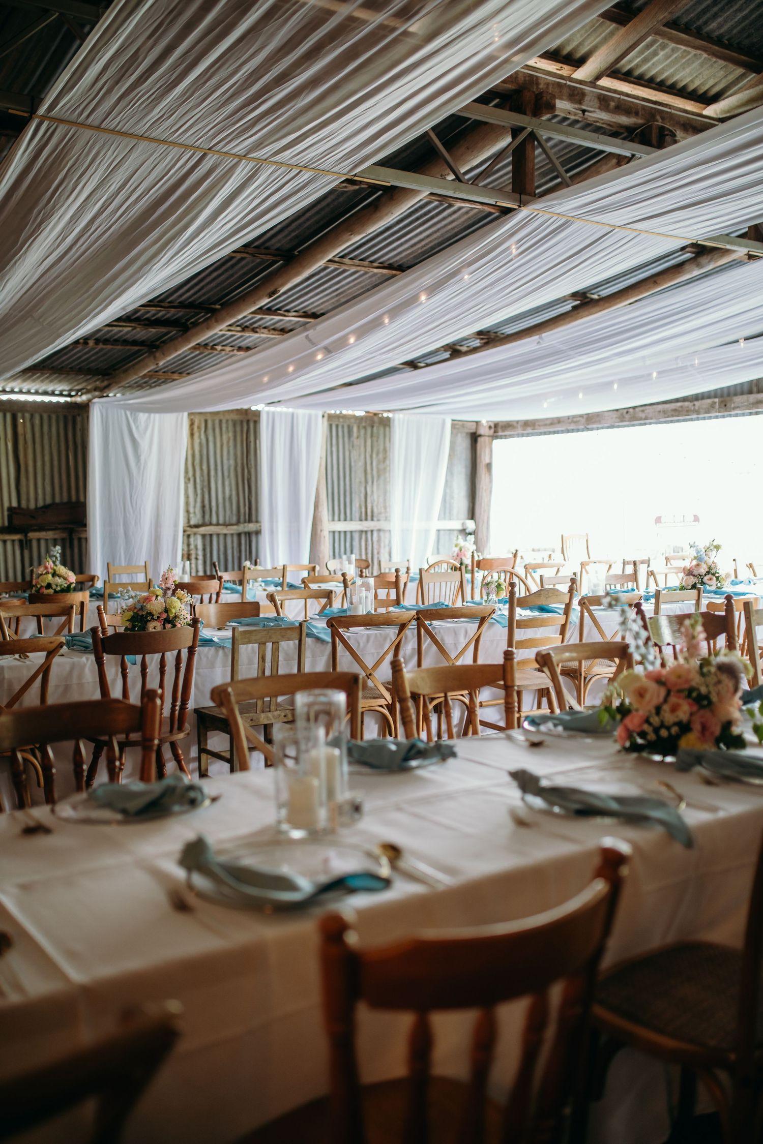 Wedding reception venue with elegant table settings and white draped ceiling.