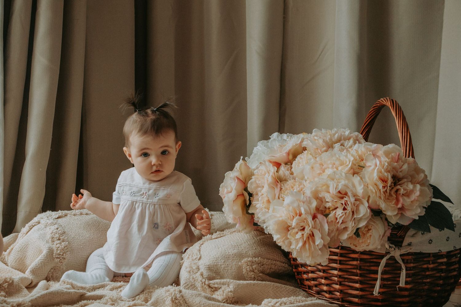 baby looking at camera sitting next to florals