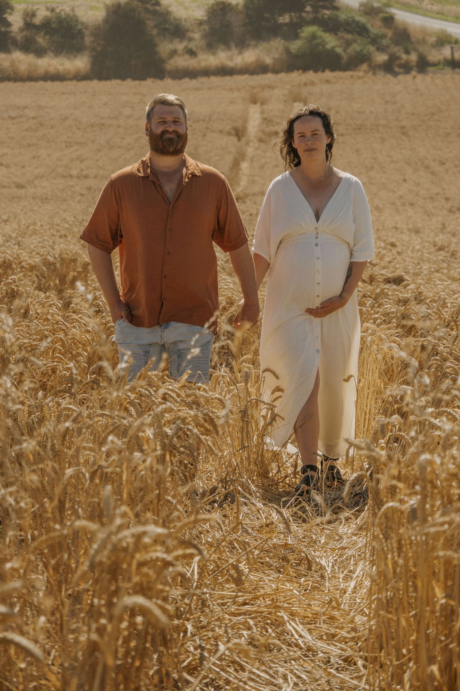 Maternity session in field, couple looking directly at camera