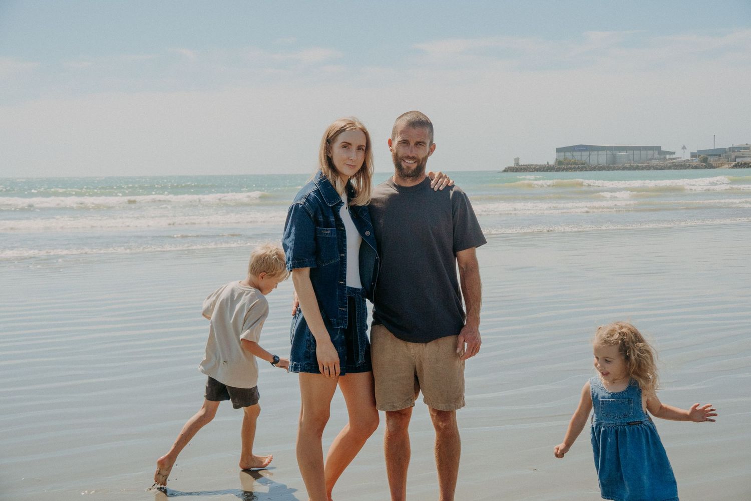 mother and father looking at camera while kids run around