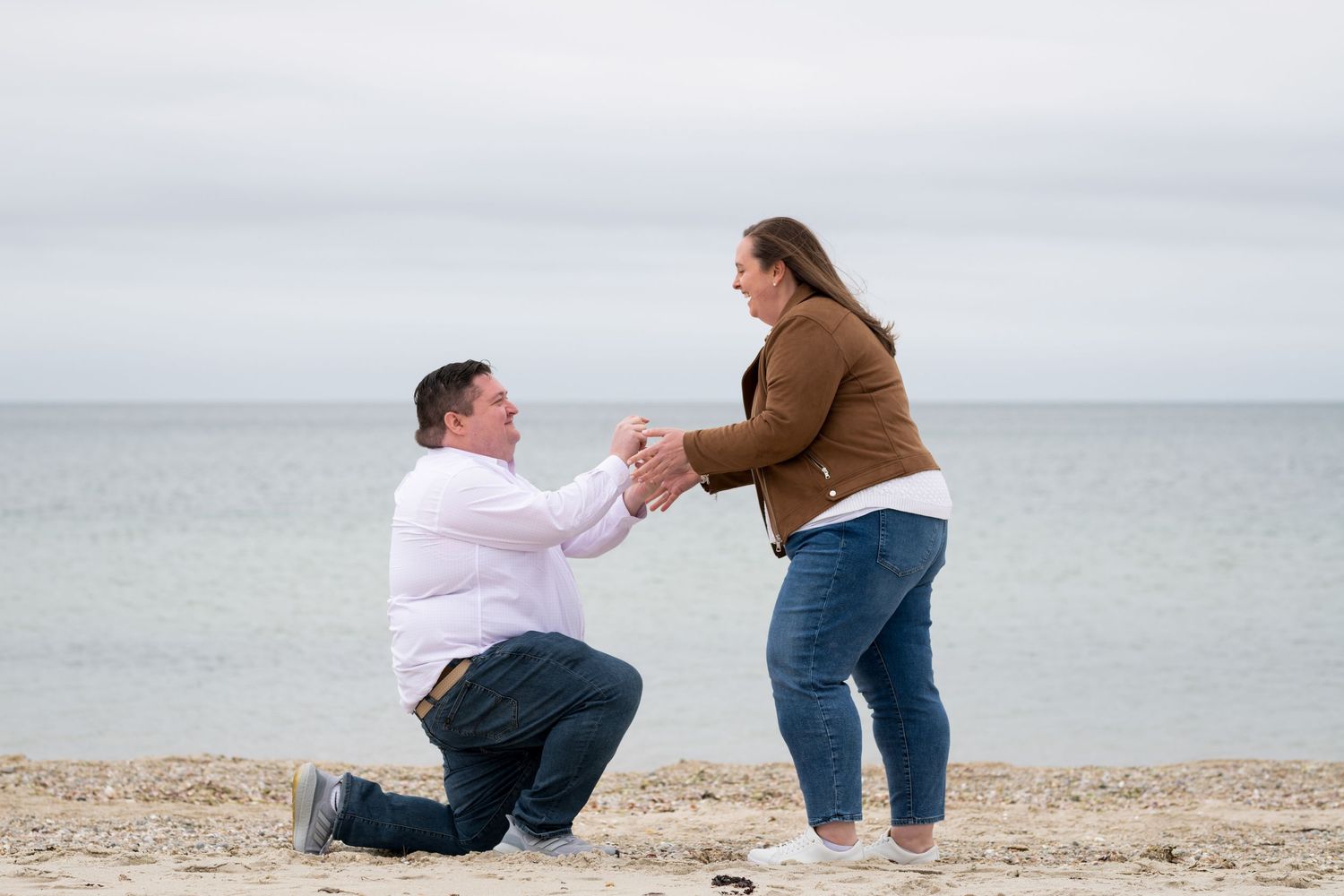 Marriage proposal scene unfolding on a sandy beach with ocean views.
