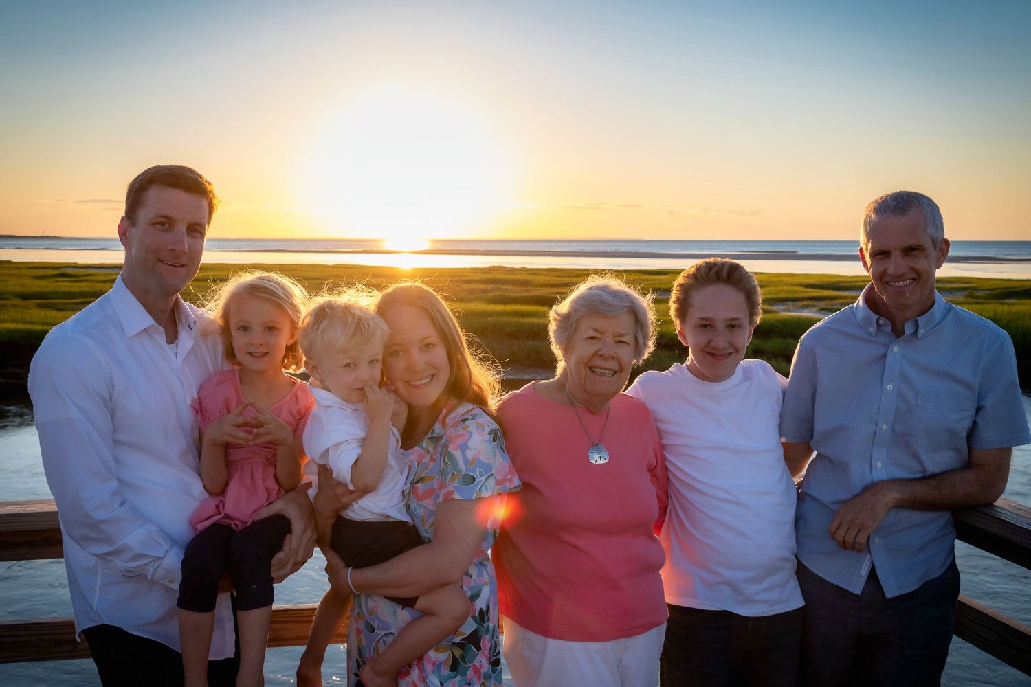 Family gathering on beach deck during golden sunset hour.