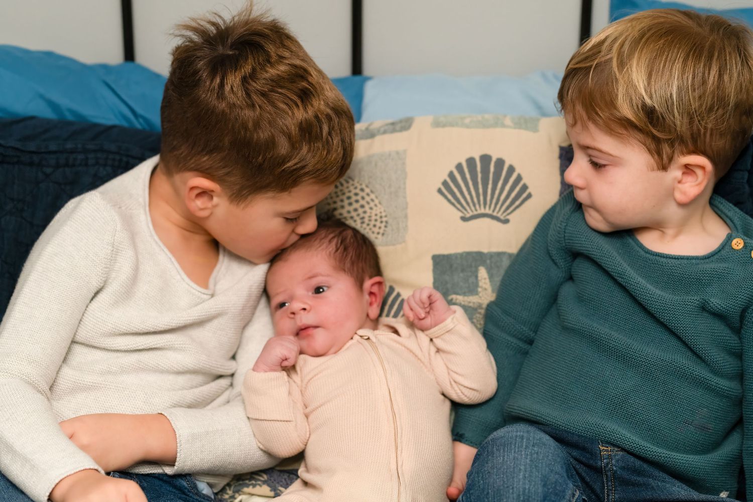 Children sharing tender moment while resting on cushions.
