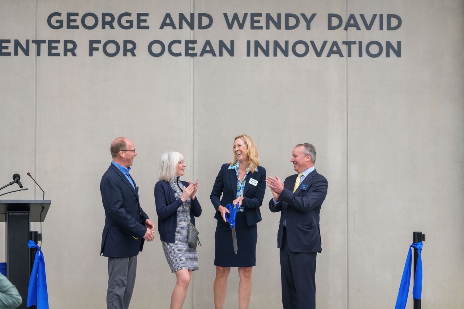 Four professionals engage in conversation during the opening ceremony of an ocean innovation center.