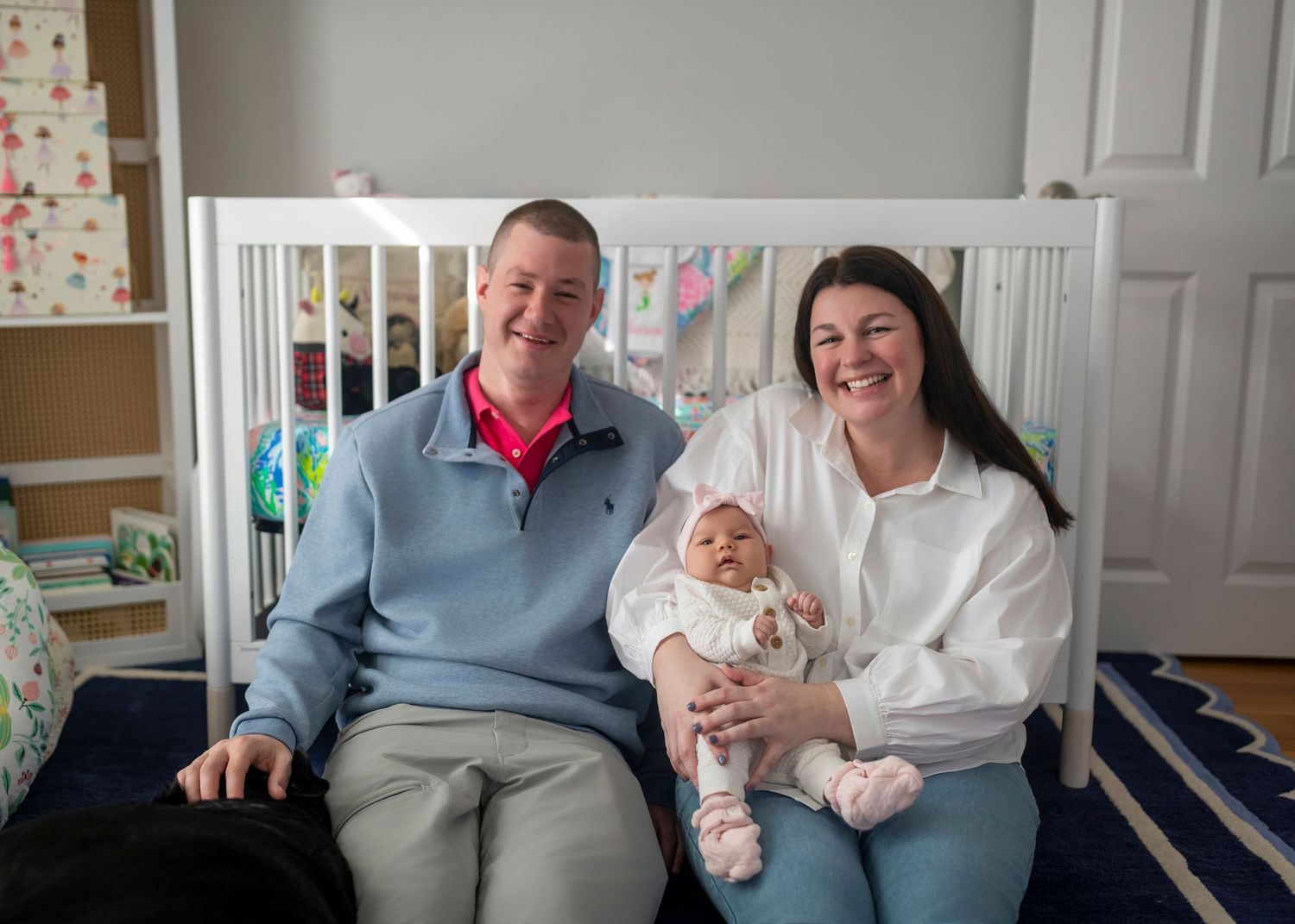 Family sitting together on grey couch in bright room with decorative wall bunting.