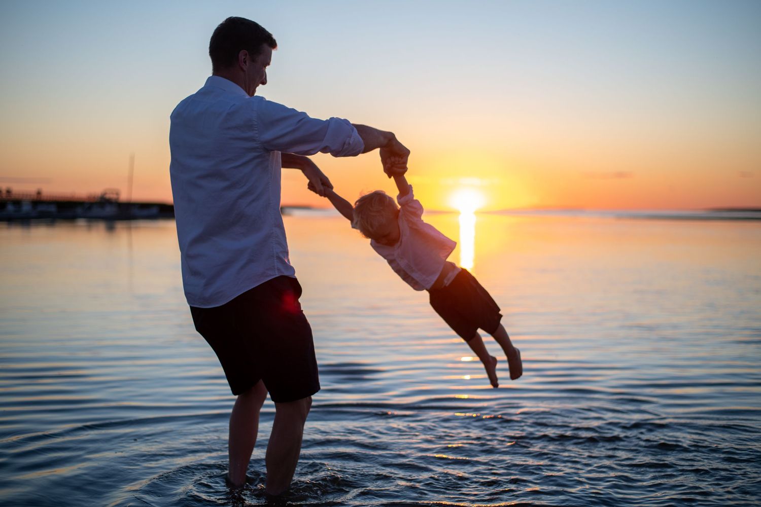 Playful silhouettes against dramatic sunset sky at water's edge.
