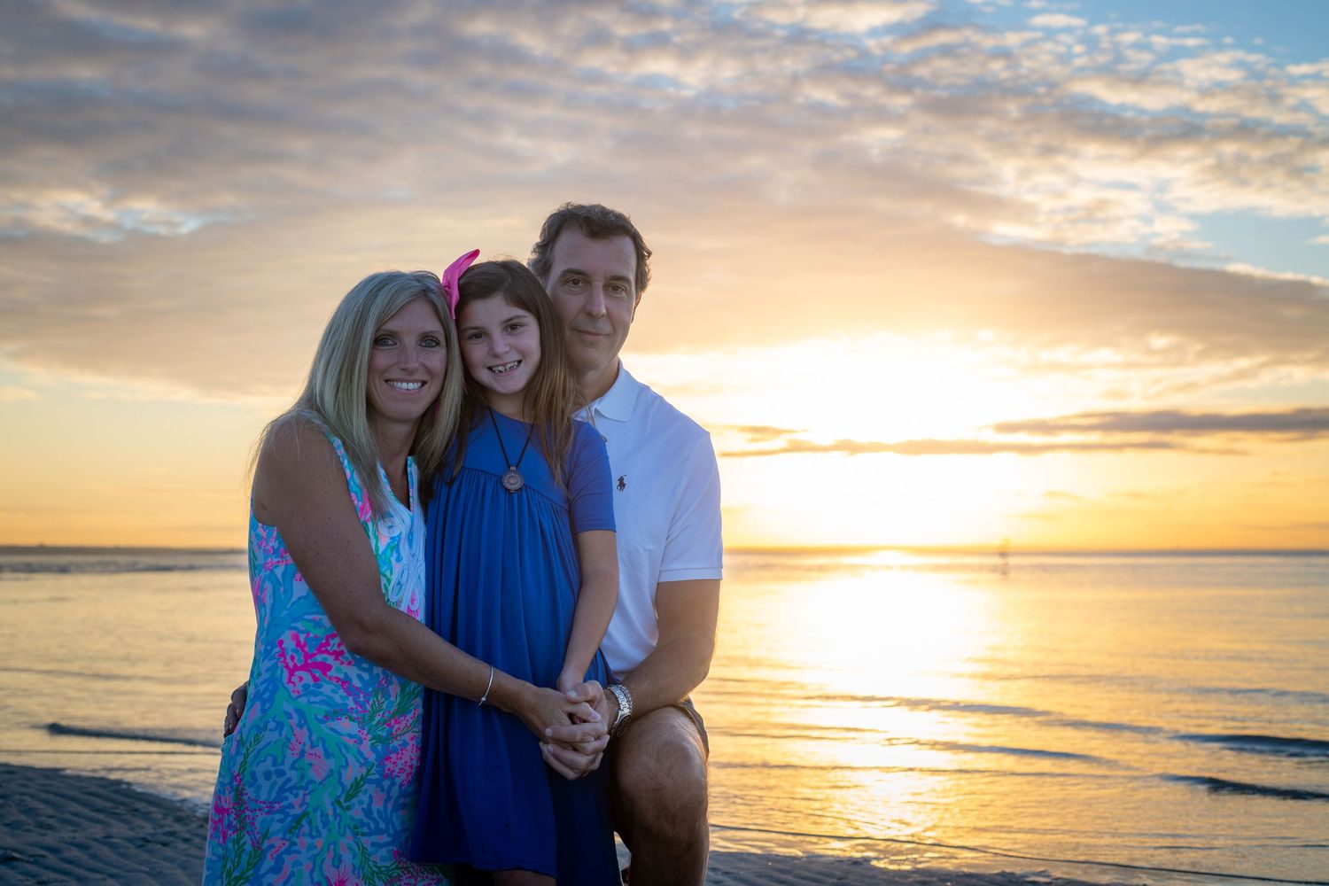 Family enjoying sunset together on beach with ocean waves.