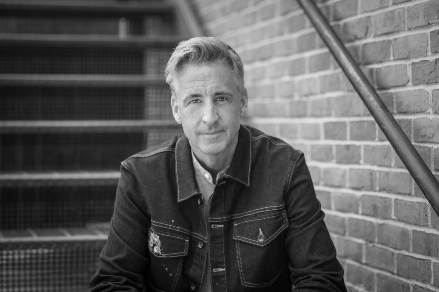 Professional headshot series against brick wall showing same person in different poses in black and white photography.