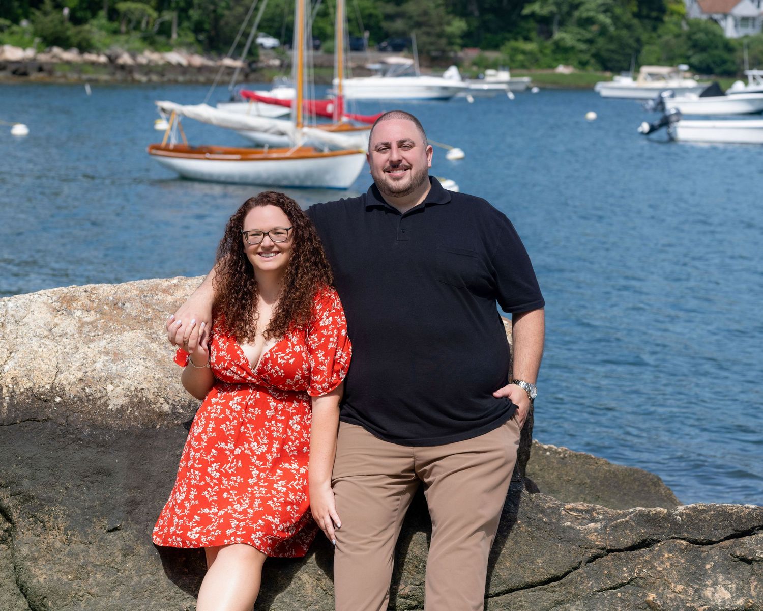 A couple enjoying a seaside moment near boats and water on a sunny day.