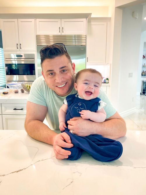 A series of four candid moments showing a parent and baby bonding while lying on a white marble countertop.