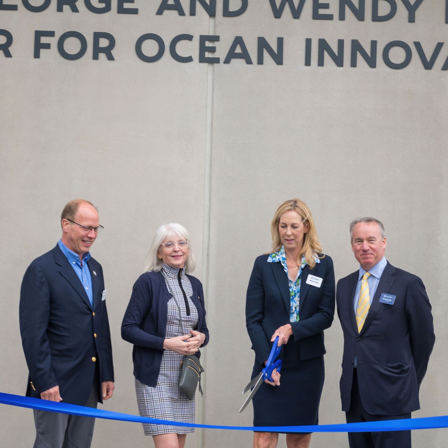 Four professionals stand at a ribbon cutting ceremony for the George and Wendy David Center for Ocean Innovation.