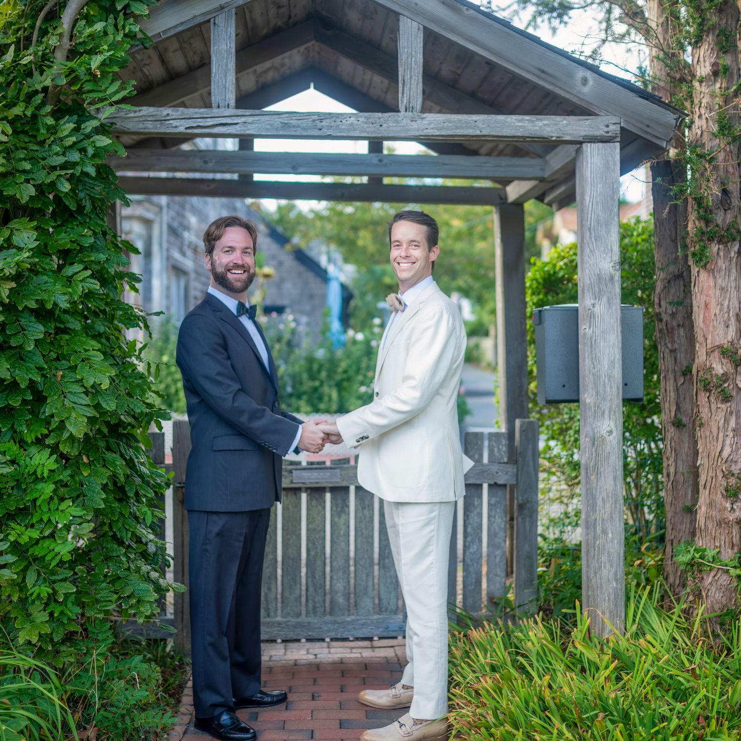 Wedding ceremony setting under a rustic wooden gazebo surrounded by greenery.