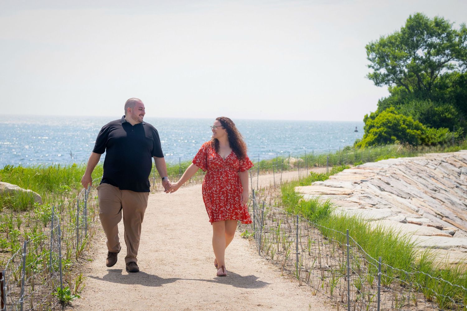 A couple walks together on a scenic coastal path with beach and ocean views.