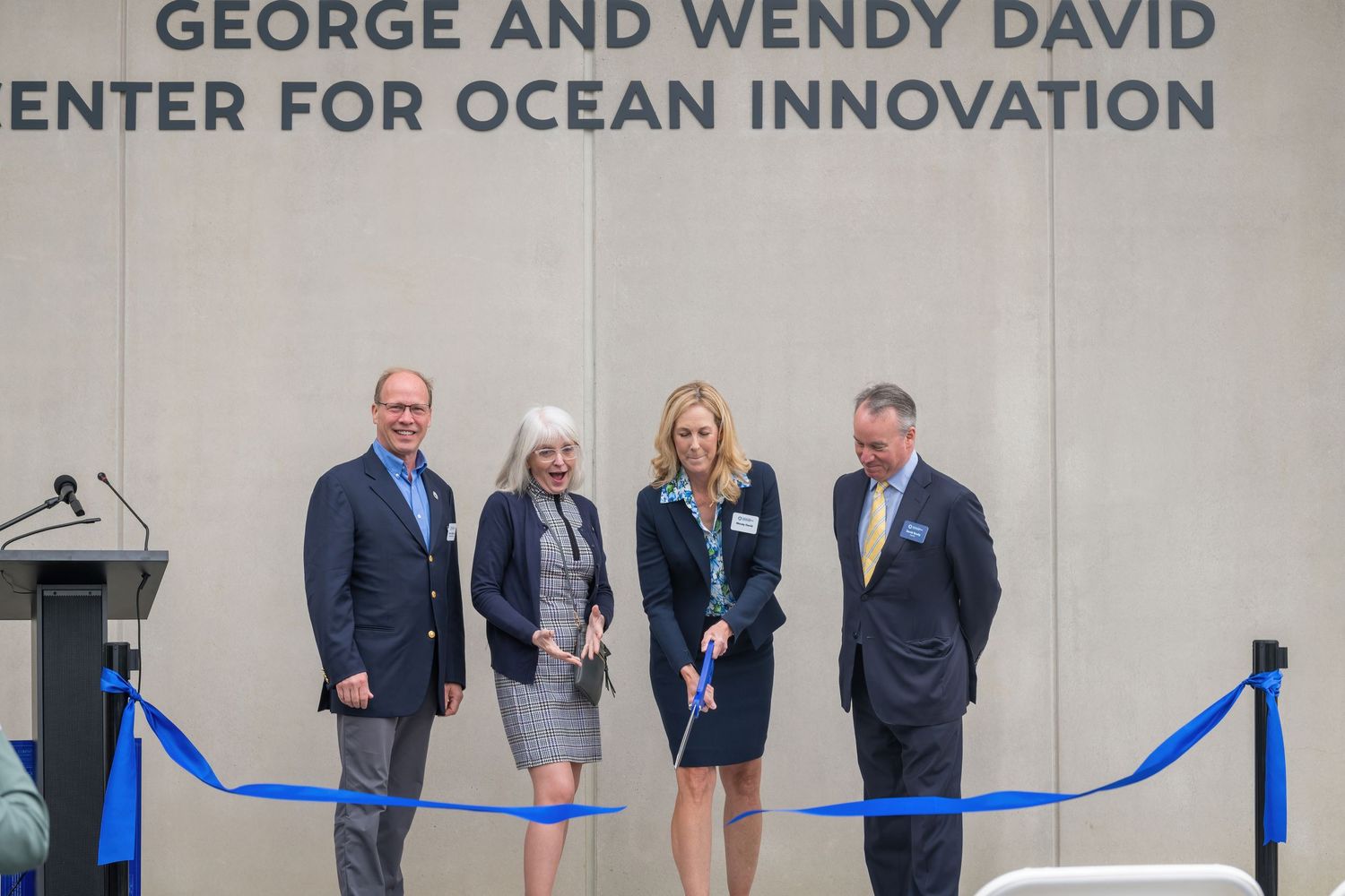 Ribbon cutting ceremony participants pose beneath the center's signage before the official opening.