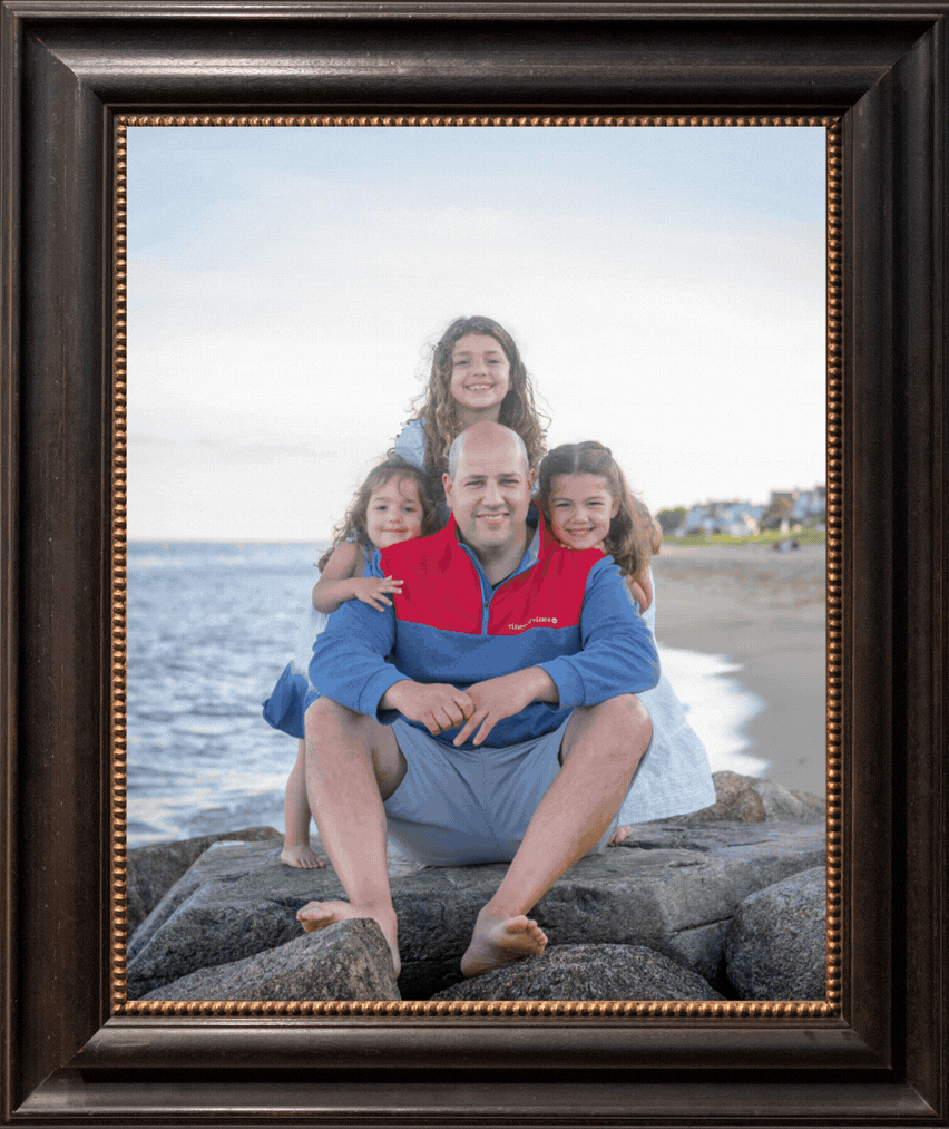 Family portrait session on rocky beach with ocean backdrop at sunset.