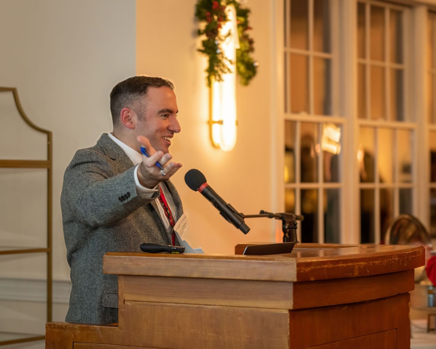 Speaker gestures while delivering remarks at a podium during an evening event.