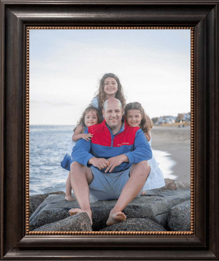 Three framed family portraits displayed side by side showing a beach setting with ocean and rocks in the background.