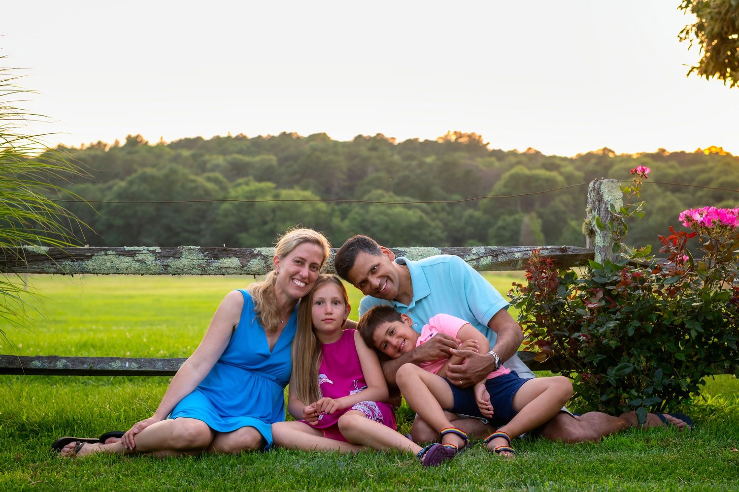 Family group lying together on grass during a summer evening photoshoot.