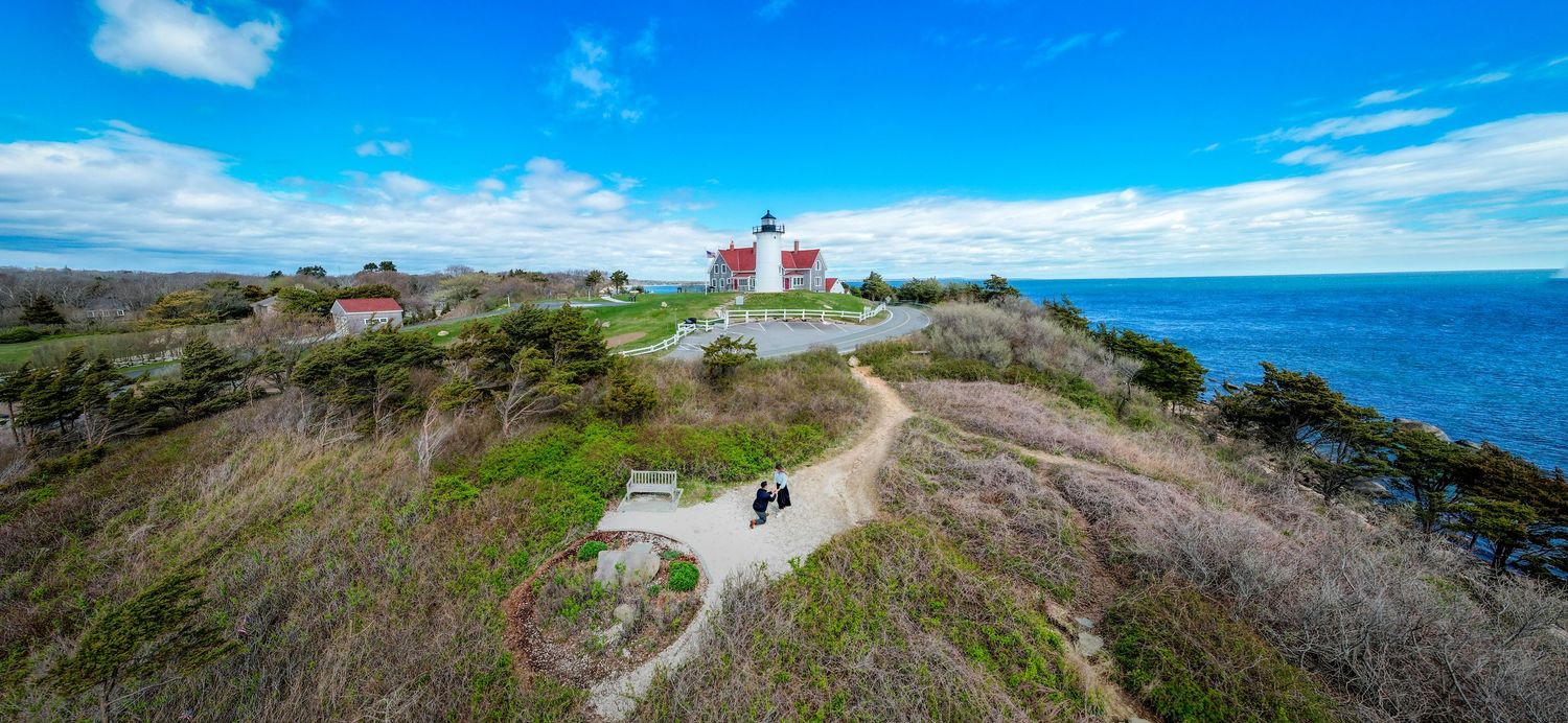 Panoramic coastal landscape with blue skies and rocky cliffs overlooking the ocean on a sunny day.