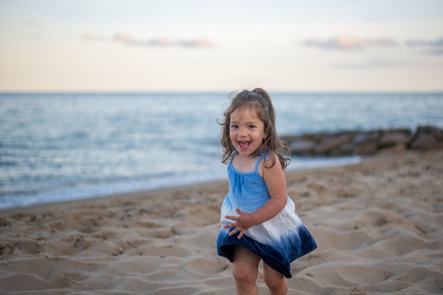 Children playing and laughing on sandy beach at sunset.