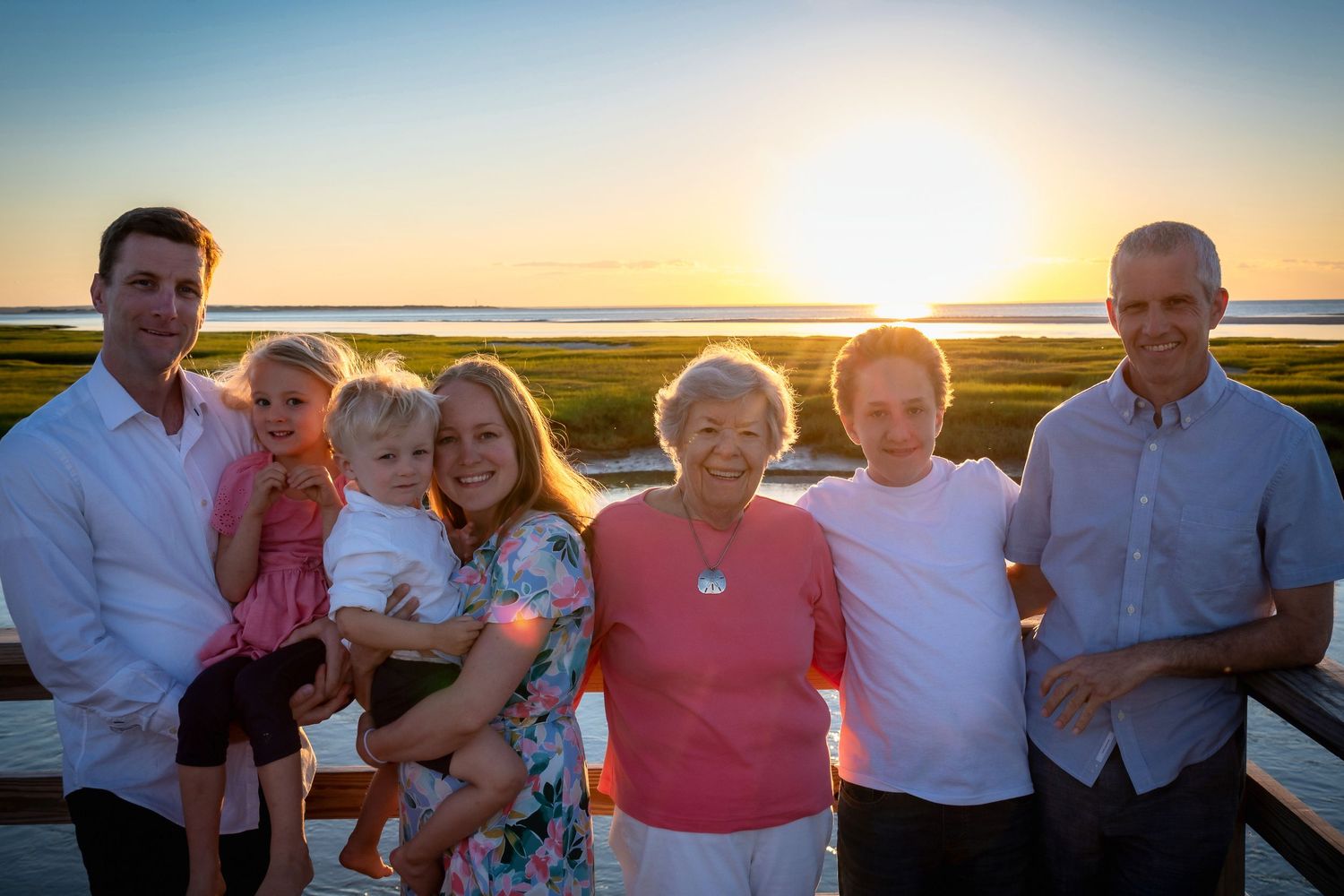 Group gathering on waterfront deck during golden sunset hour.