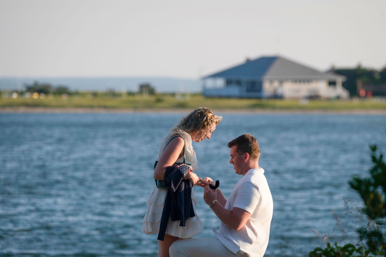Proposal moment captured by the water with coastal homes visible in the distance.