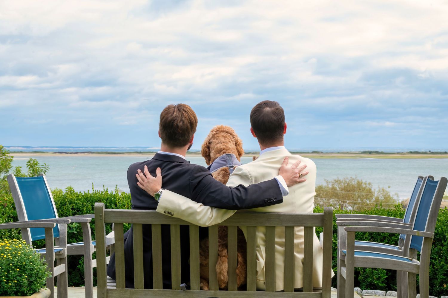 People sitting together on wooden benches overlooking a scenic coastal landscape.