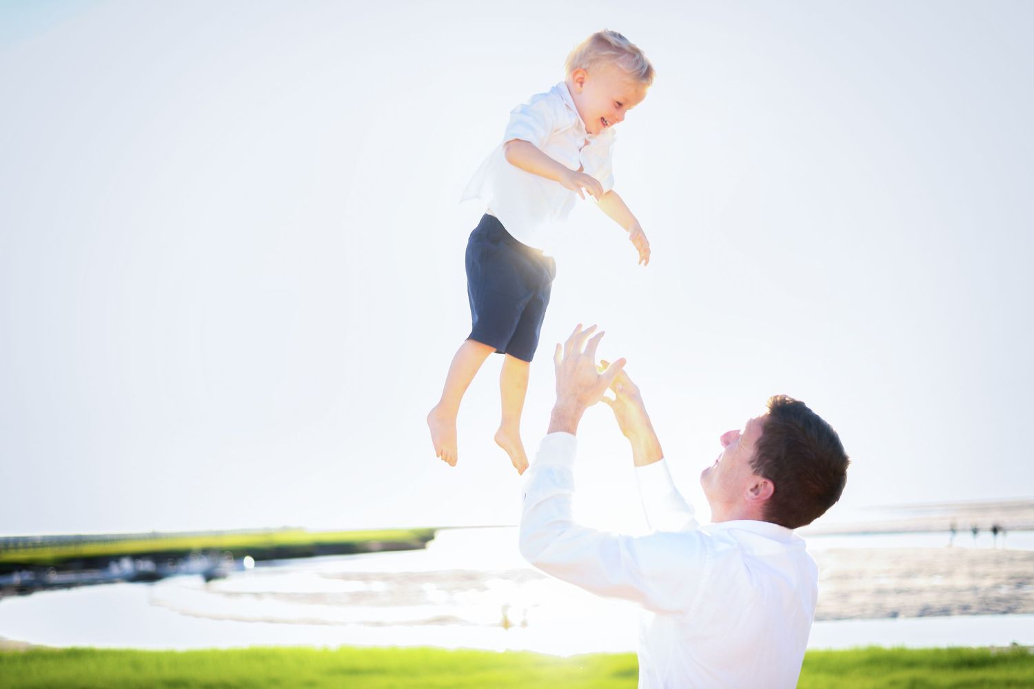 Joyful family moments captured in white outfits against bright sky background.