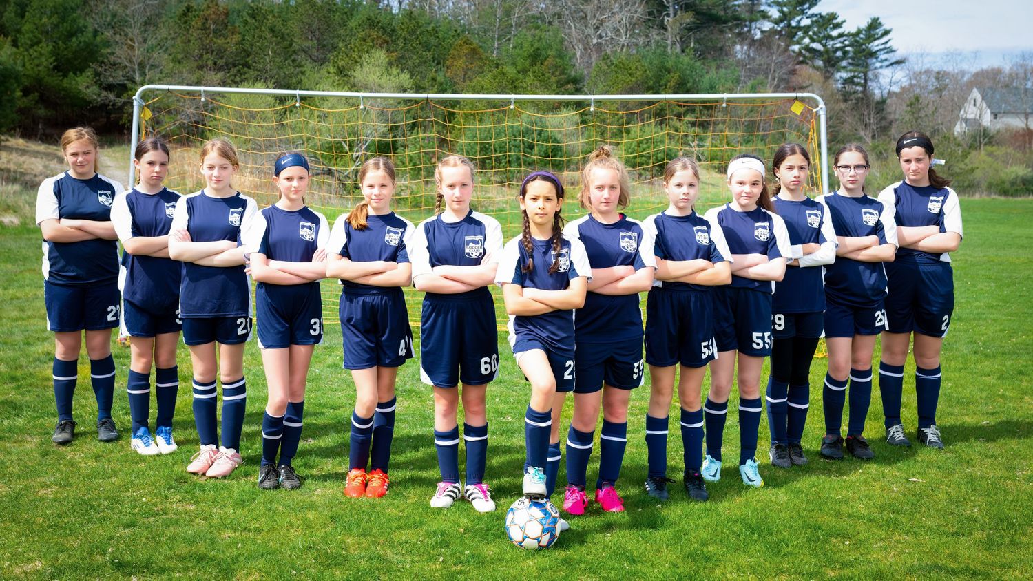 Rugby or sports team lined up in navy blue uniforms on a grass field.