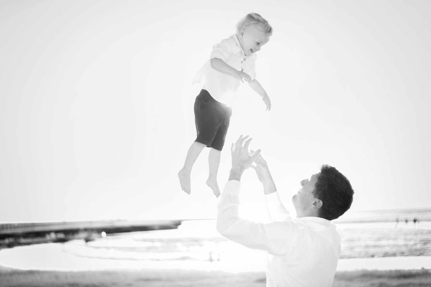 Black and white silhouettes of people playing and jumping on a bright background.