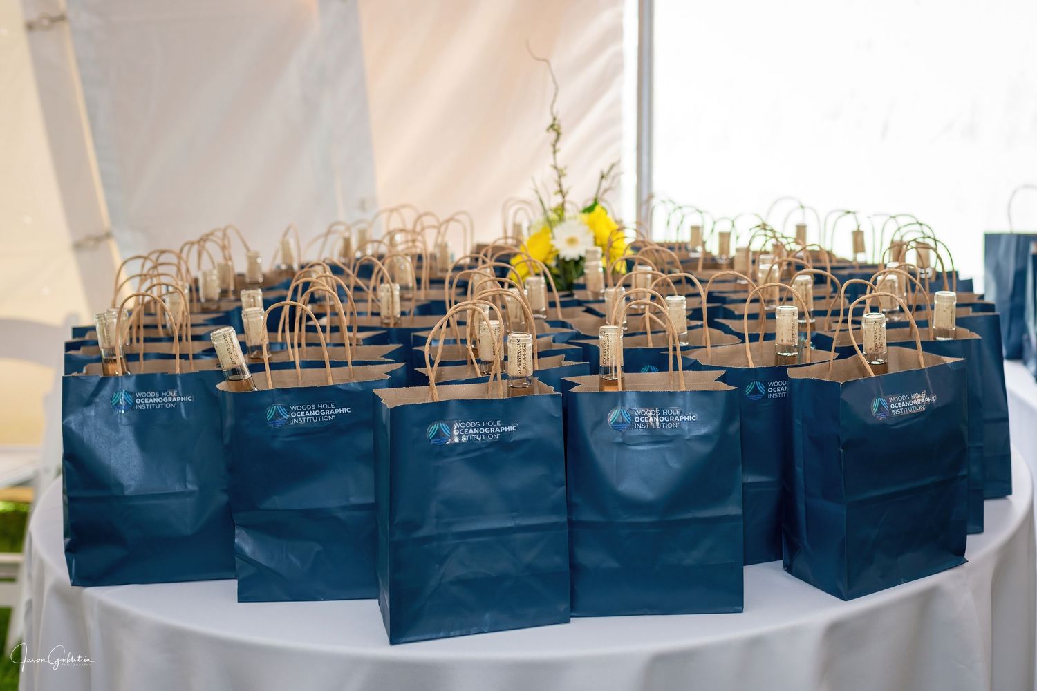 Row of blue gift bags lined up on display tables at an event.