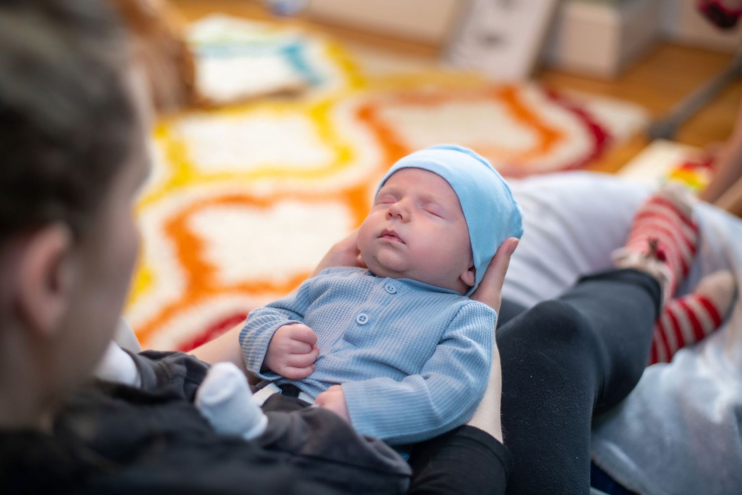 Sleeping infant in light blue outfit resting on orange patterned surface.