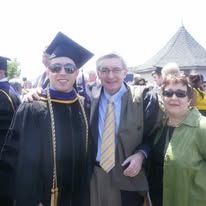 Graduates in black caps and gowns gather together outdoors during a commencement ceremony celebration.