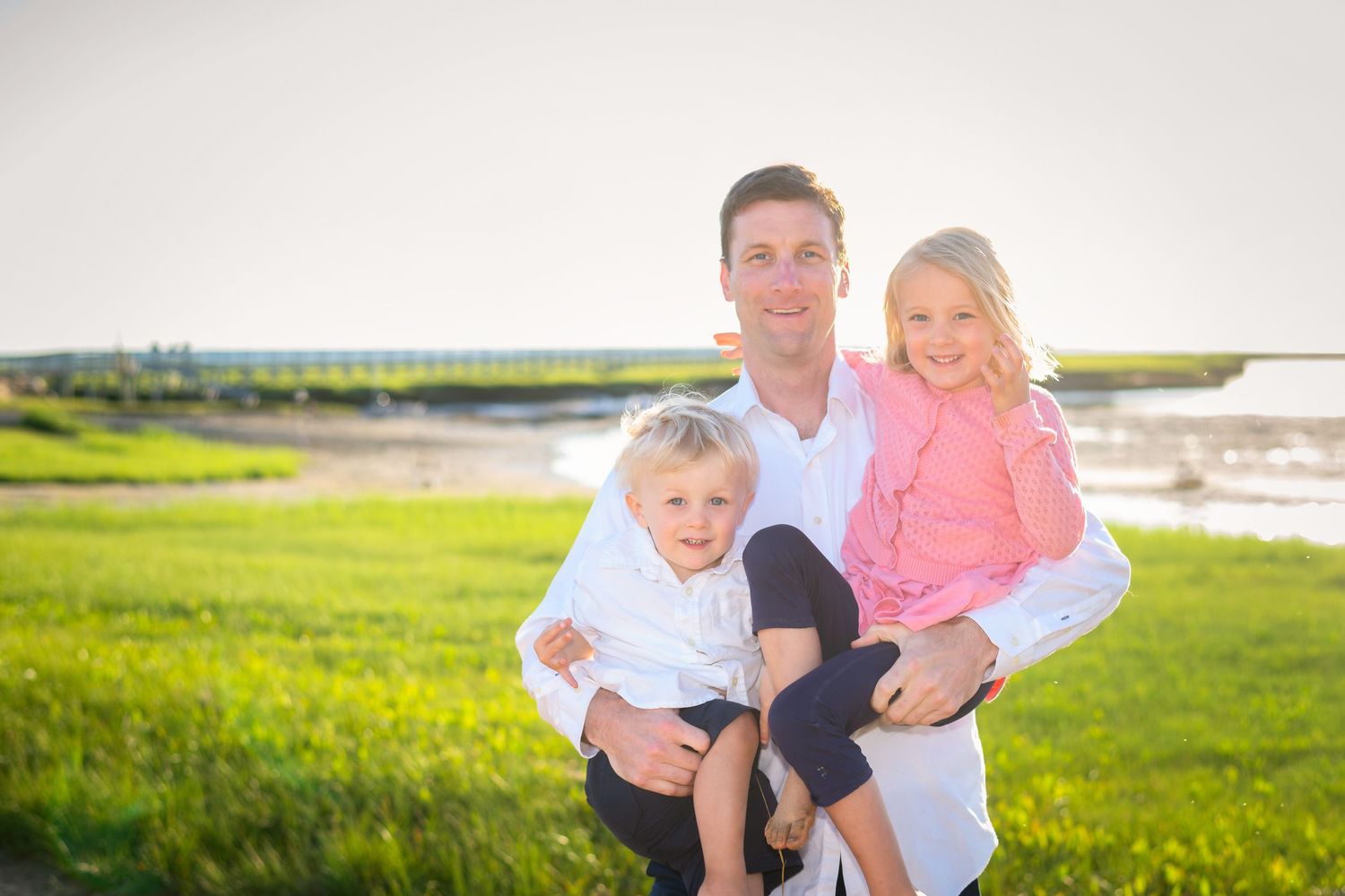 Family enjoying a sunny day together on grassy waterfront area.