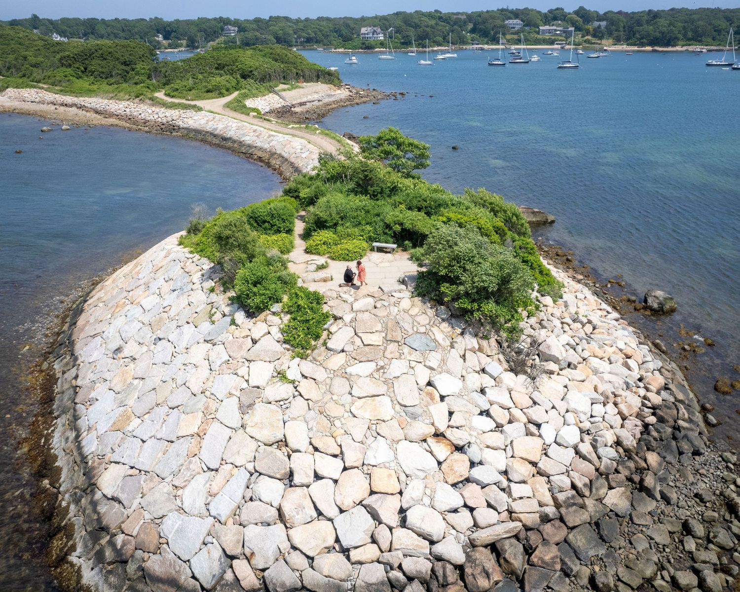Scenic aerial view of stone jetty extending into blue ocean waters.