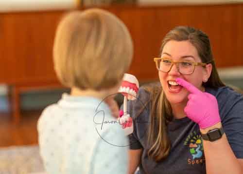 Speech therapist using dental model to teach young child proper tongue placement.