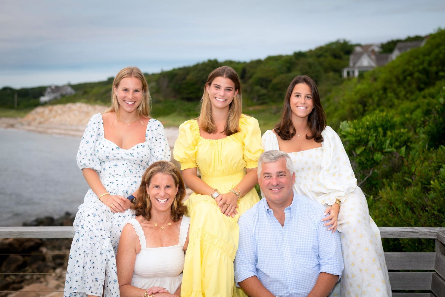 Multi-generational family gathering on a wooden deck overlooking a scenic coastal landscape.