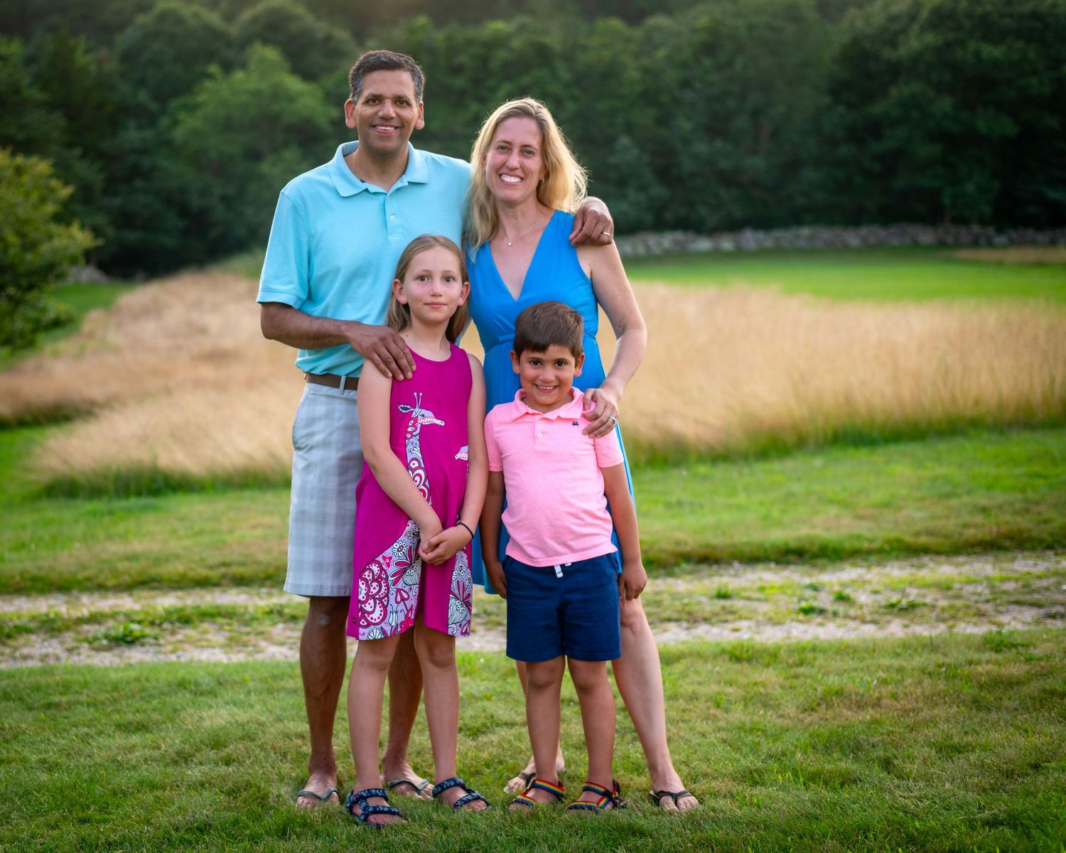 Family group photo taken in a green field during summer.