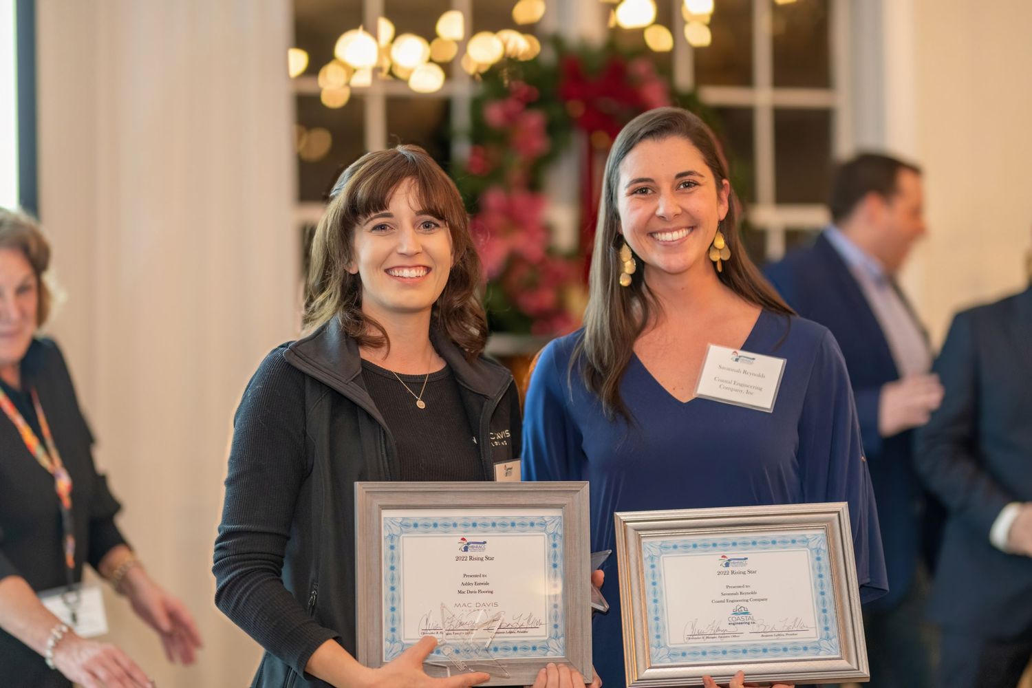 People receiving awards and certificates at a formal recognition ceremony with chandeliers overhead.