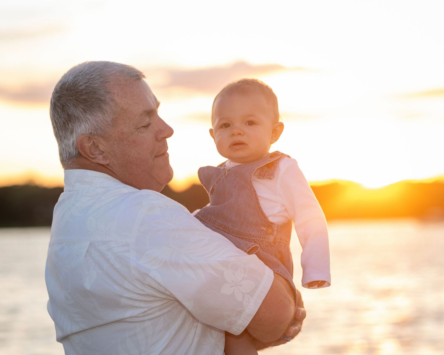 Family embracing on beach at golden sunset with warm glowing light in background.