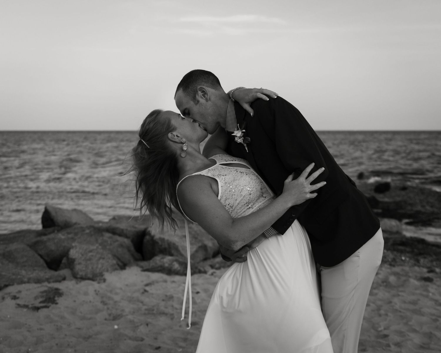 Black and white romantic beach scene with ocean waves in background.
