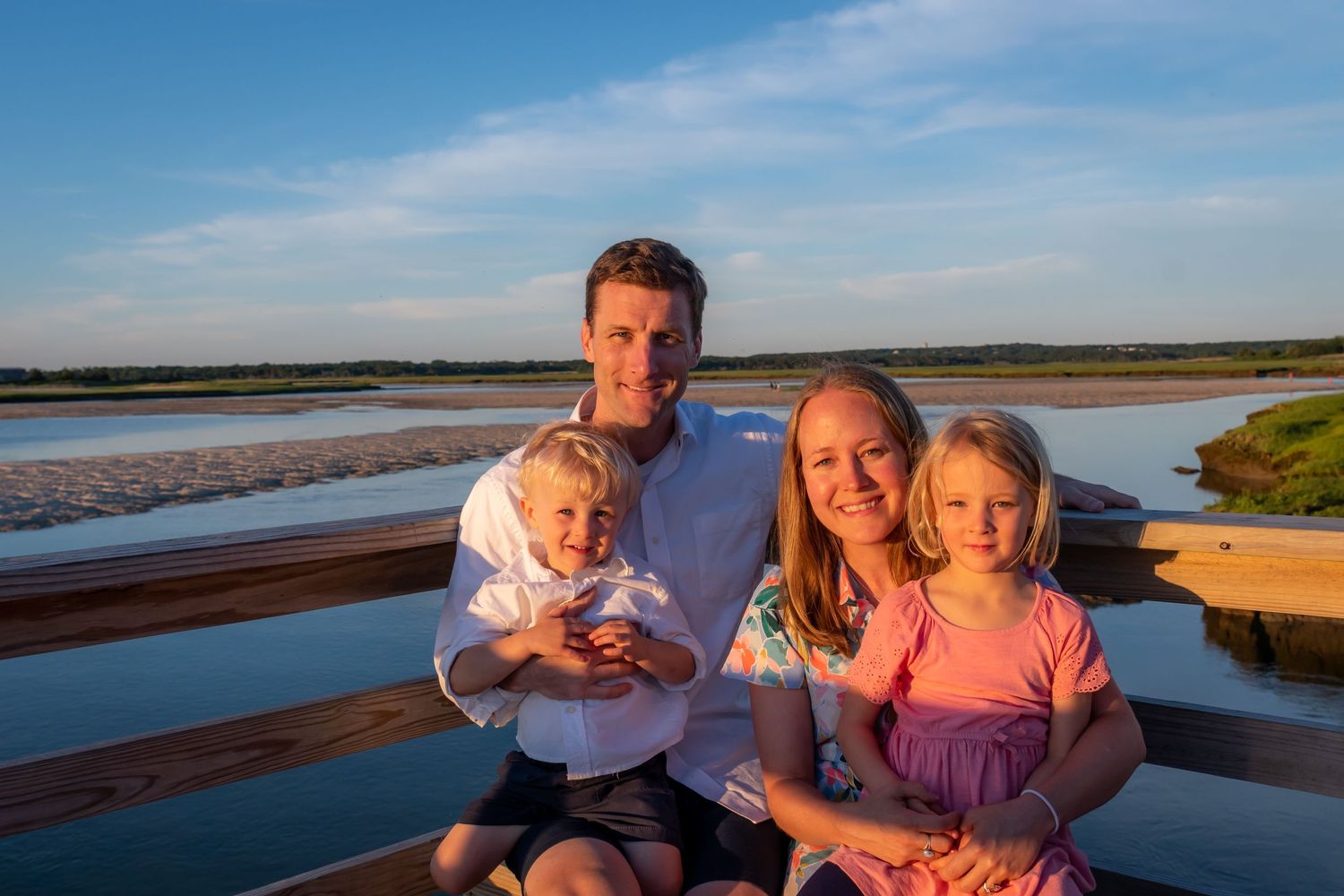 Group portrait taken at the beach during golden hour with water and sky in background.