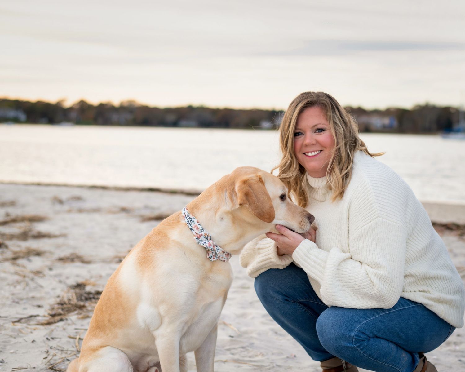 A golden retriever plays with someone on a beach during sunset.