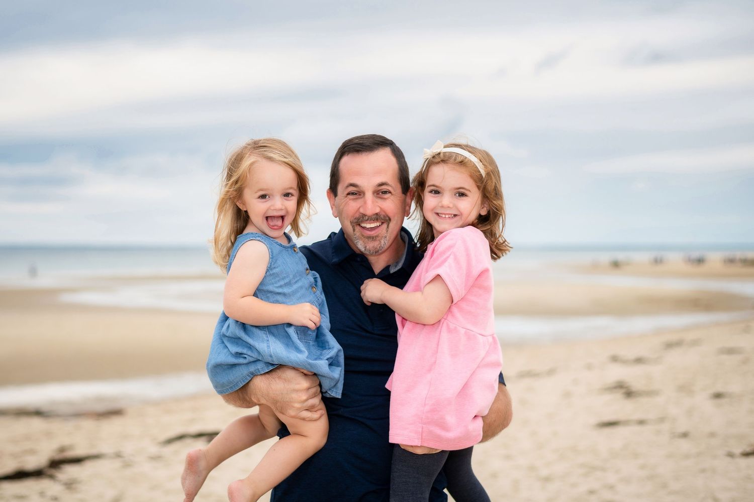 Family enjoying a sunny day together at a coastal beach with blue skies and sandy shores.