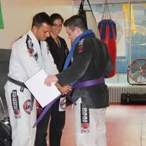 People practicing martial arts and self-defense techniques in a training facility with colorful mats and equipment.