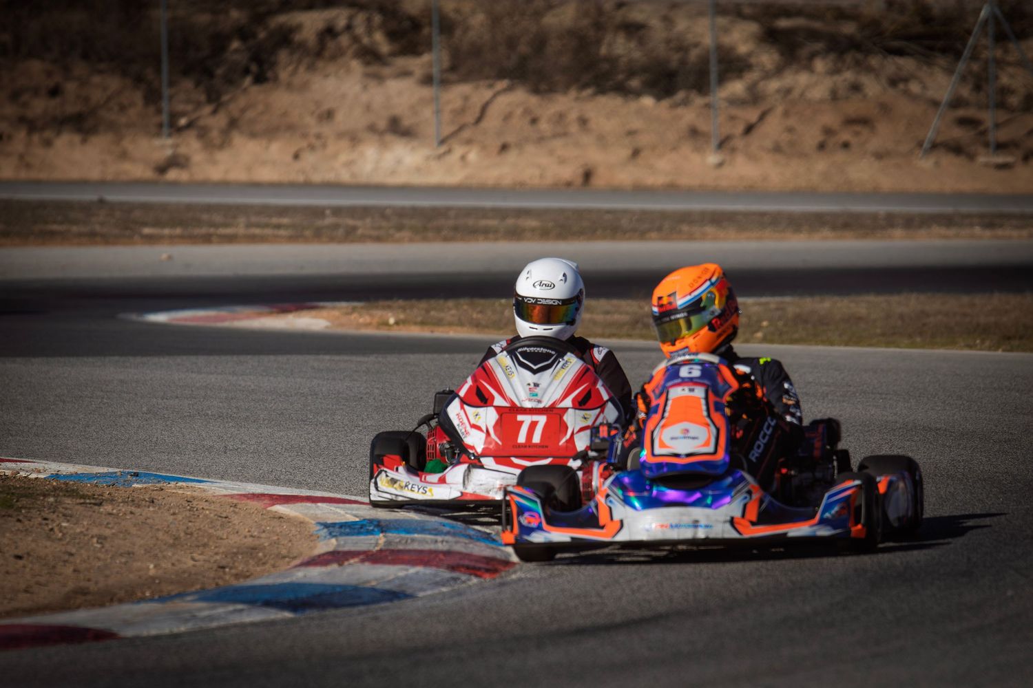 Go-karts racing on a winding track during a competitive event.