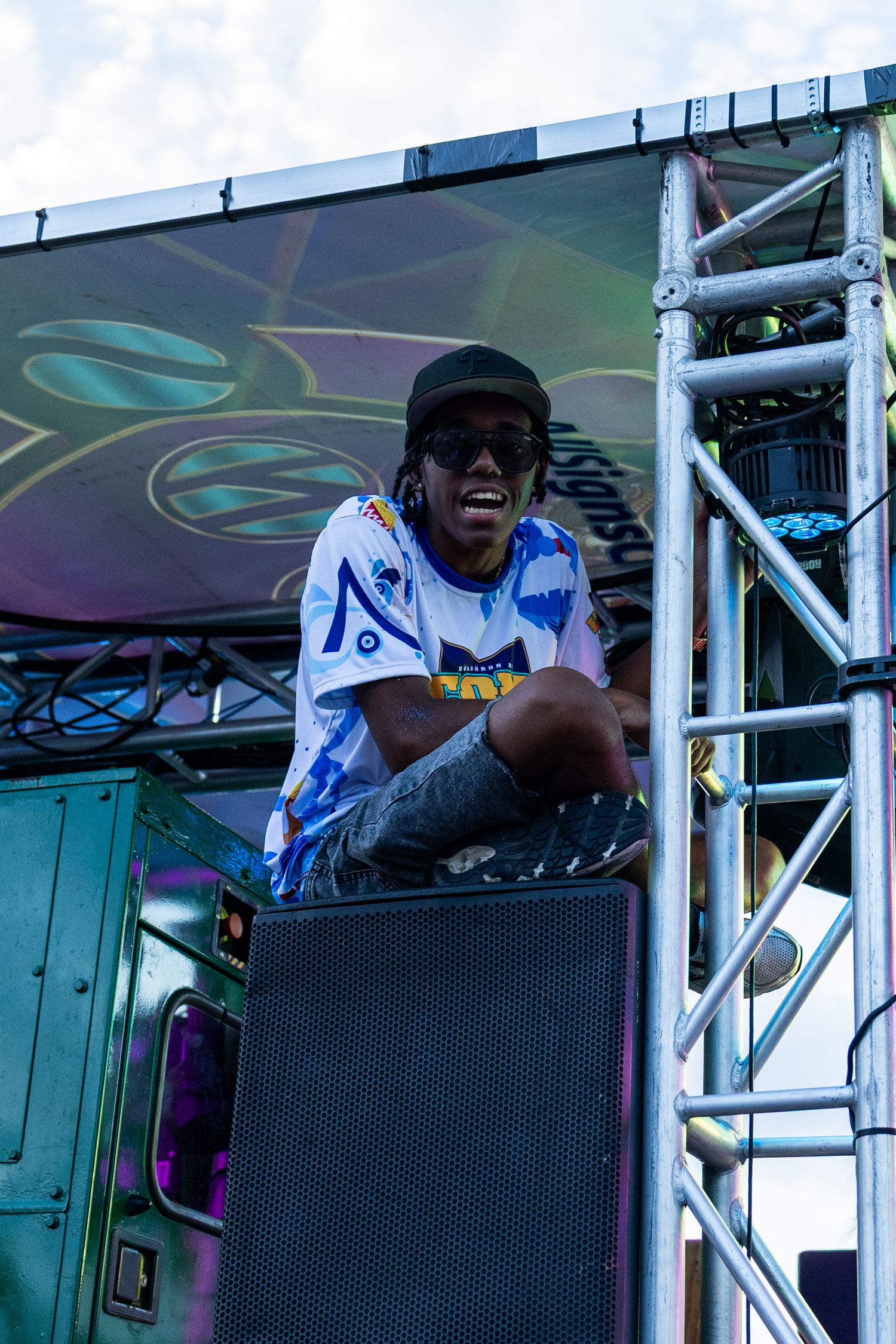 Festival performers on elevated stage with lighting and sound equipment.