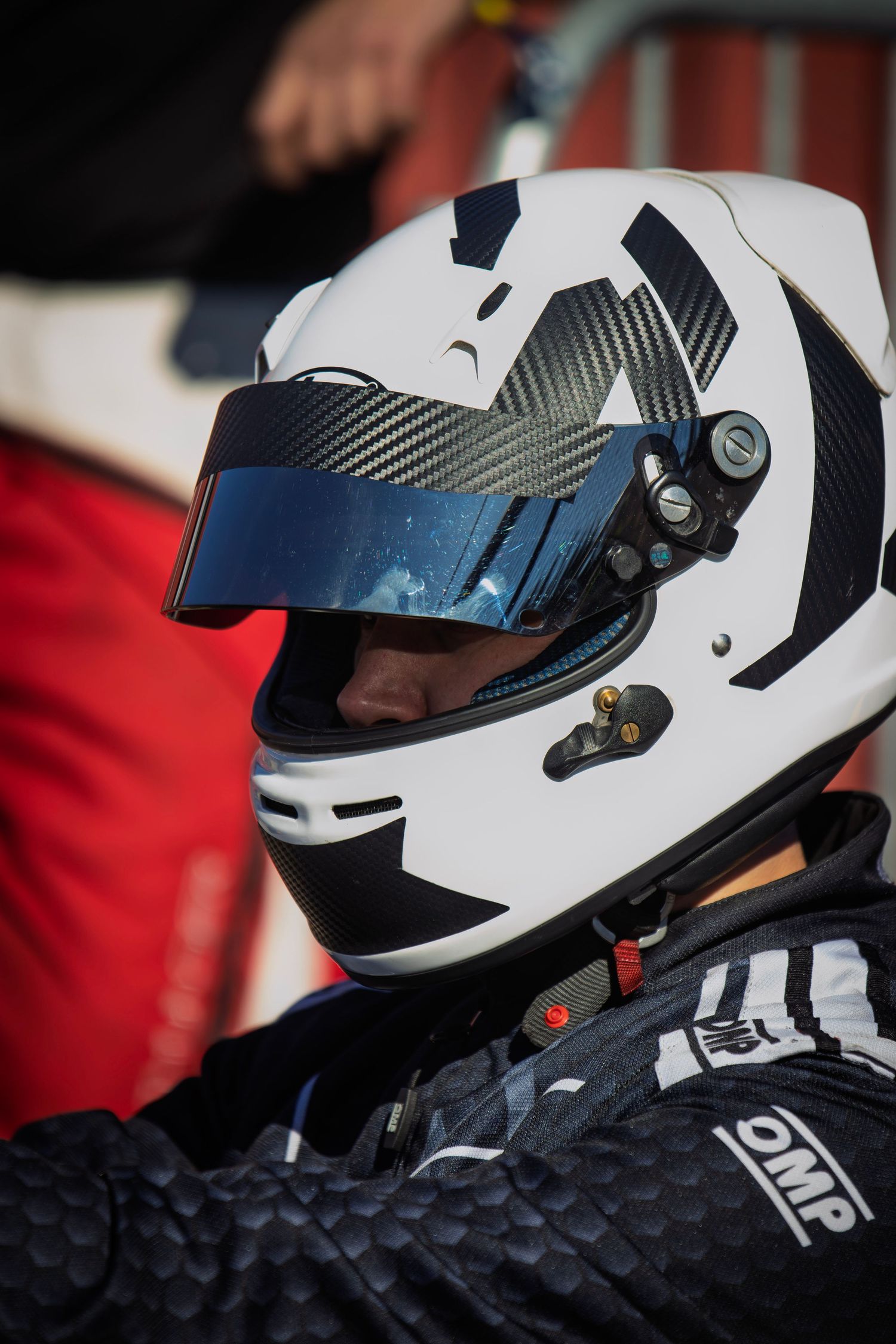 White racing helmets with visors displayed in a row against red background.